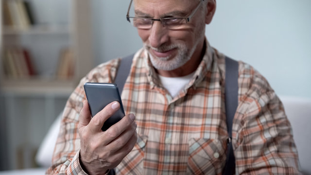 Happy old man holding phone, learning modern technologies, easy app for elderly