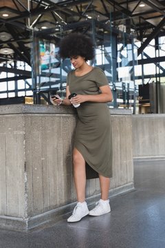 Afro young woman using smartphone while standing indoors