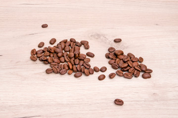 Fragrant roasted coffee beans chaotically scattered on a light wooden board