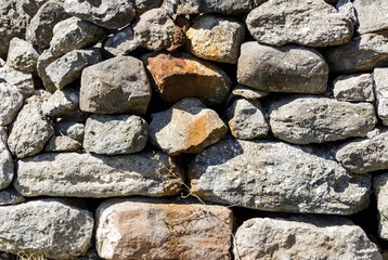The wall of the ancient fortress is made of stones. Texture.