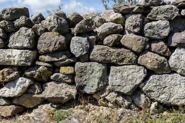 The wall of the ancient fortress is made of stones. Texture.