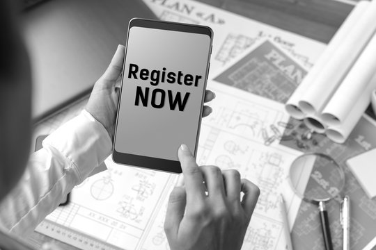 A girl (architect, student, businesswoman) at a table with business accessories, accessories for drawing (plans, rulers) and training with tablet with text Register now