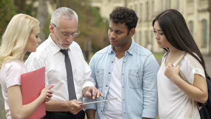 Senior teacher showing new educational app on tablet to students, MBI studies