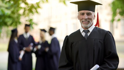 Aged man in graduation outfit, professor obtaining new degree, academic career