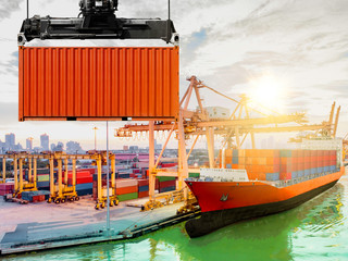 Crane lifting up container ship cargo containers loading to harbor in sunrise, with export and...