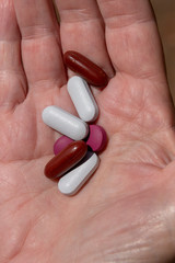 A close up view of a womens plam of her hand holding seven pills
