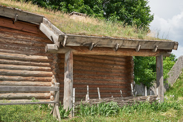 Fragment of a wooden log building with an earthen roof