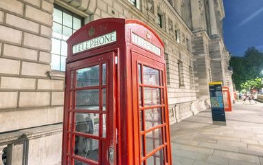 Fototapeta na wymiar Red telephone booth at night in a London street, UK