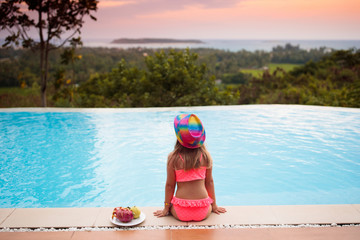 Child at swimming pool at sunset. Kid at sea.