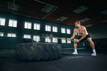Fototapeta na wymiar Shirtless young fit man flipping heavy tire at gym. The exercise, fitness, sport, workout, athlete, power, training, bodybuilding concept
