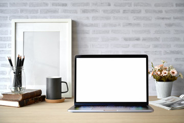 Creative desk workspace with blank picture frame poster, blank screen laptop for graphic display montage