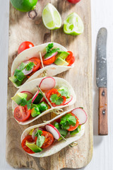 Top view of tasty tacos with cherry tomatoes and radish