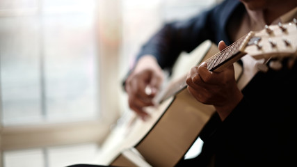Fototapeta na wymiar Cropped shot of man practicing in playing acoustic guitar