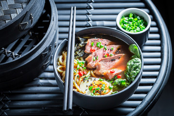 Tasty Ramen soup with beef and eggs on black table