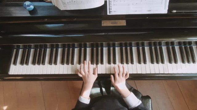 Top perspective of a little girl practices piano lessons. Slow motion