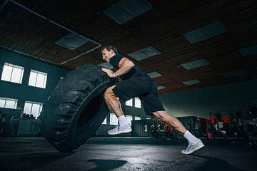 Shirtless young fit man flipping heavy tire at gym. The exercise, fitness, sport, workout, athlete, power, training, bodybuilding concept © master1305