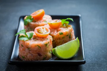 Foto auf Glas Closeup of salmon tartare with lime and cherry tomatoes © shaiith