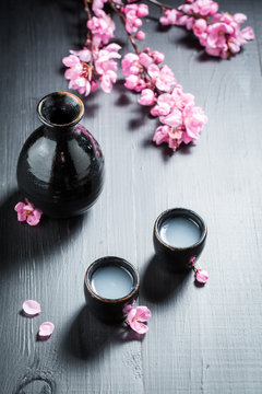 Unfiltered sake in dark ceramics and blooming flowers