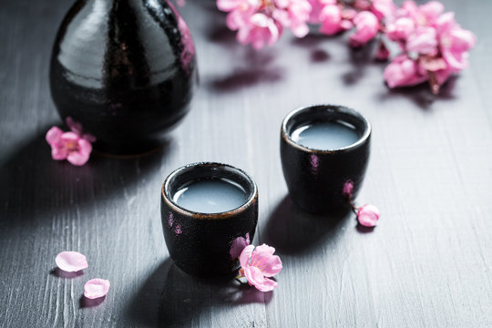Closeup of sake in black ceramics and blooming flowers