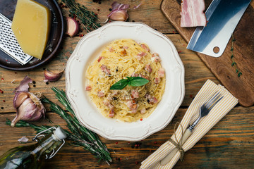 Spaghetti Carbonara. Pasta alla carbonara with a cream sauce, bacon and pepper on a white plate. Old wooden background
