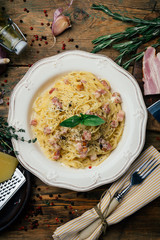 Spaghetti Carbonara. Pasta alla carbonara with a cream sauce, bacon and pepper on a white plate. Old wooden background