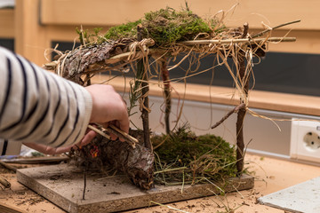 Child is making a crib on branches and moss for Christmas
