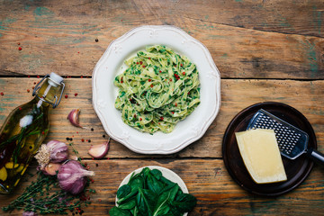 Spinach Fettuccine. Vegan pasta with spinach (Spinach Fettuccine Alfredo Pasta) on a white plate. Old wooden background