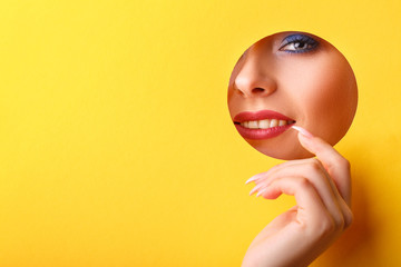 Woman looking in the hole, bright beautiful makeup, big eyes and lips, bright lipstick,...