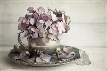 Originalfoto im Vintage-Stil von malvenfarbenen getrockneten Hortensien in einer angelaufenen silbernen Vase © Janice