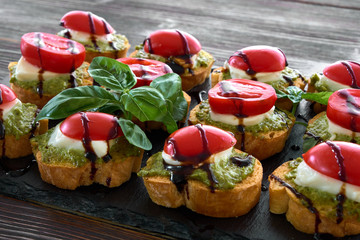 caprese toasts on a black plate