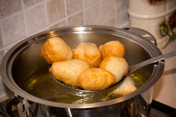 Dipper taking off Dough from a Pot after Friying during the Preparation of an Italian Christmas Traditional Dish called Pettole