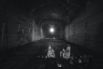 Underground tunnel of an old abandoned bomb shelter with ice stalagmites on the floor. Black and...