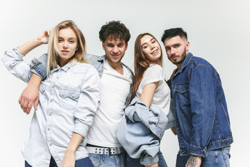 Group of smiling friends in fashionable jeans. The young men and woman posing at studio. The fashion, people, happy, lifestyle, clothes concept