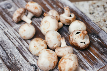 Champignon mushrooms. Small white brown mushrooms on wooden table. 