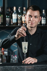 bartender making French 75 Cocktail. Mixing ingredients in a glass. Bar on a background