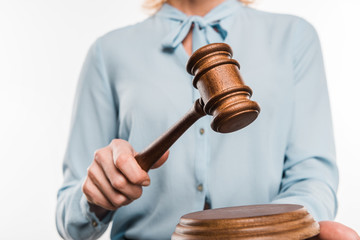 cropped shot of female judge holding wooden hammer isolated on white