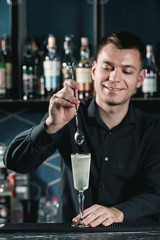 bartender making French 75 Cocktail. Mixing ingredients in a glass. Bar on a background