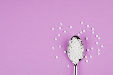 Sugar-replacing tablets with a spoon on a  purple background.