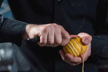 bartender making cocktail. slicing a long ribbon of lemon peel