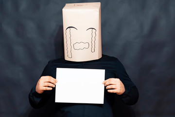 The concept of emotions. A man holds a blank white sheet in front of him. On the face, an expression of resentment and pity.