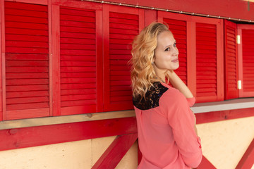 Portrait of a beautiful young woman on the background of a red wooden wall