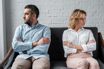 mad couple sitting on couch after quarrel and looking away