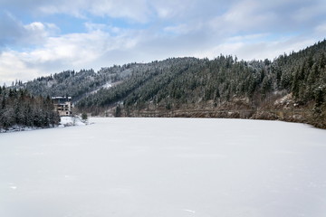 Solitary hotel building in a beautiful snowy winter landscape with forest and frozen Brezova dam