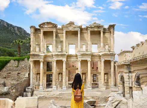 A young Asian tourist woman wearing yellow dress enjoying the view at Library of Celsus at Ephesus which is an ancient Roman building in Ephesus, Anatolia and now part of Selçuk, Turkey.