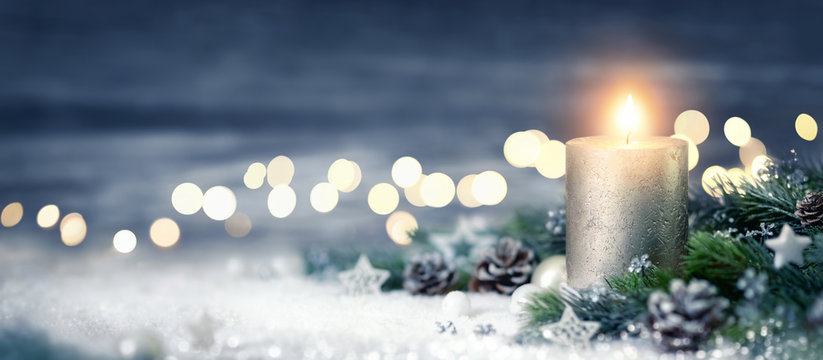 Dekoration für Weihnachten mit Kerze und Lichtern auf Schnee und Holz