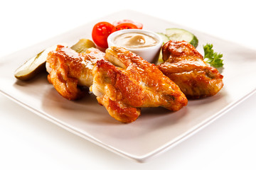 Grilled chicken wings with vegetables on white background