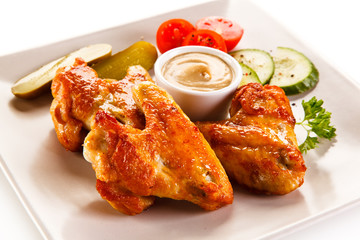 Grilled chicken wings with vegetables on white background