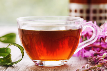 Herbal drink Ivan-tea in a transparent cup close-up on wooden table