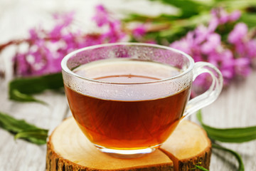 Traditional Russian herbal drink Ivan-tea in a transparent cup close-up on wooden table