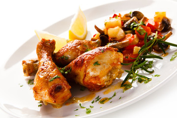 Grilled chicken drumsticks with vegetables on white background